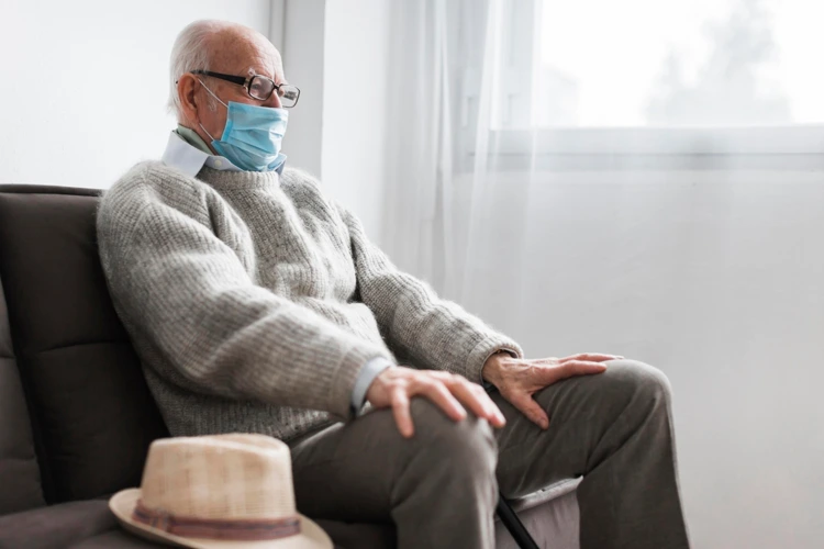 Elderly man with mask on sitting down to wait for his turn for doctor consultation.