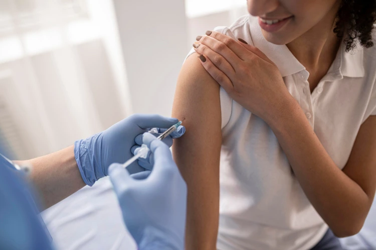 Nurse administering influenza vaccine to female patient at clinic.